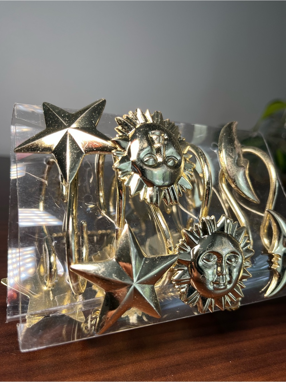 A set of 12 gold-toned metal shower curtain hooks with sun, stars and moon.